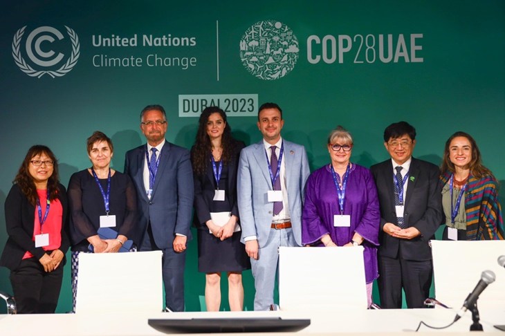 ponentes de un evento de la COP28 delante de un mural con los logos del evento de naciones unidas