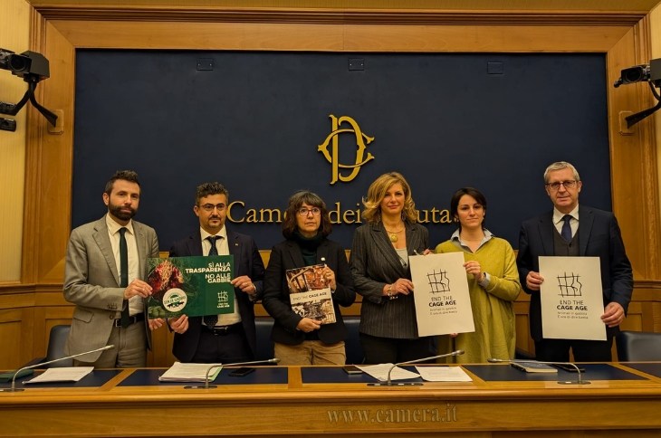 un grupo de personas en la sala de conferencias del Parlamento Italiano sosteniendo pancartas con inscripciones